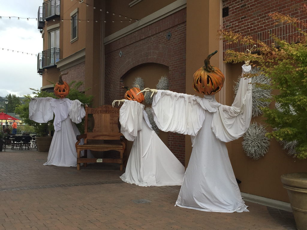Pumpkin-headed figures draped in white fabric outside a brick building in Napa.